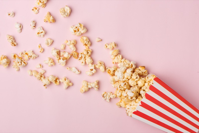 Popcorn in red and white cardboard box on the pink background