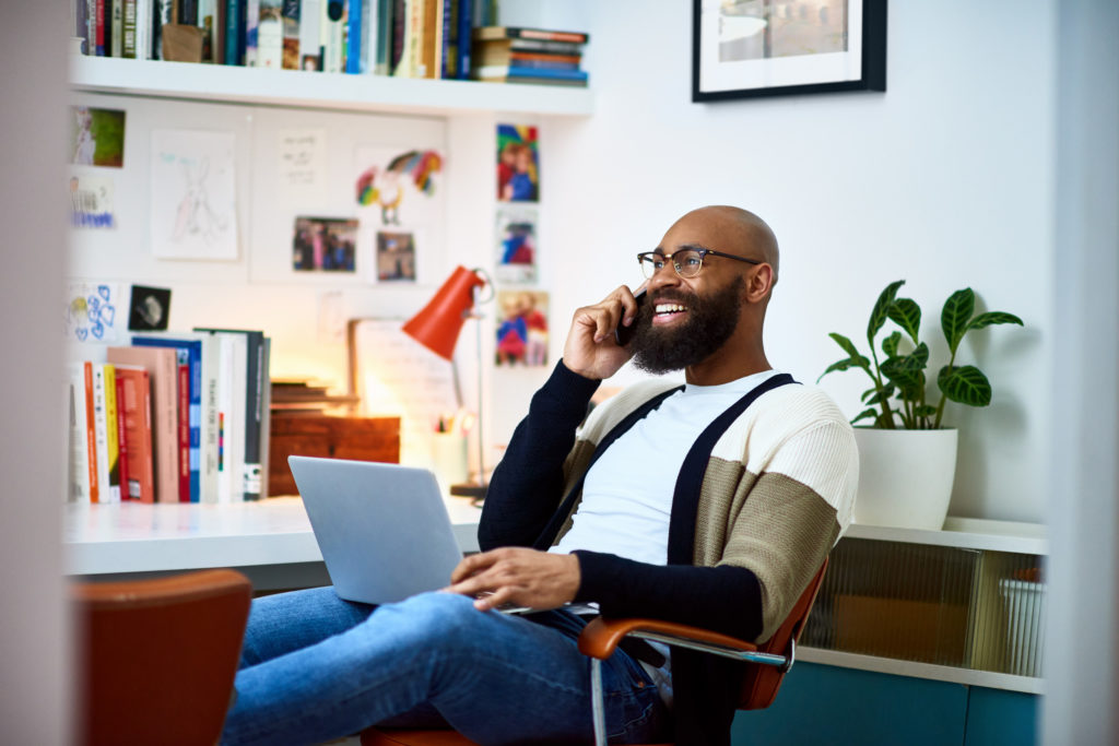 Man in his 30s sitting on chair with laptop, on phone call, communication, owner, entrepreneur